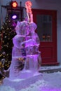 Vertical view of illuminated ice sculpture representing a cat playing the cello seen at night during the winter carnival