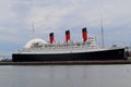 The Queen Mary docked at the Long Beach Harbor on a cloudy afternoon.