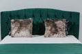 Queen-size bed with deep green velvet headboard and fluffy cushions