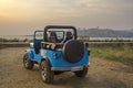 Blue SUV convertible on the background of the concrete promenade and the ocean during sunset