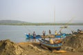 Indian men extract sand in the river way. boat loaded with sand in the water near the shore