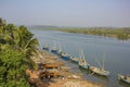 Indian workers extract sand in a river way, large blue boats off the river and trucks