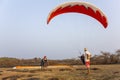 Preparation for take-off tandem paraglider on the background of dry savanna and a landing man on a