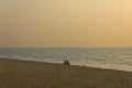 Two friends are sitting on a sandy beach against the background of the ocean and the gray bright