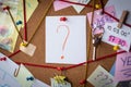 Question concept. Close-up view of a detective board with evidence. In the center is a white sheet attached with a red pin with