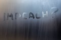 The question impeach written on wet window glass close-up with blurred background