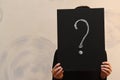 A question mark drawn on a black Board that covers a person`s face Royalty Free Stock Photo