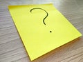 Question mark message on yellow sticky note on wooden background
