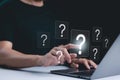 Question Mark and Problem Solving Concept. A person using a laptop with floating question marks, symbolizing brainstorming, Royalty Free Stock Photo