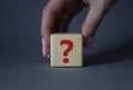 Question mark symbol. Concept words question mark on wooden cube. Businessman hand. Beautiful grey background. Business and