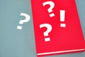 Question marks and exclamation mark next to a book on a textured paper background
