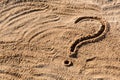 Question marks written on beach sand close up, with copy space