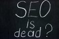 The phrase `SEO is dead?` on a dark background chalk boards. An important issue for the younger generation of copywriters Royalty Free Stock Photo