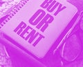 The question to Buy or Rent typed on a cover of book, eyeglasses and pen. analysis of real estate market and personal Royalty Free Stock Photo
