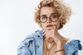 Questioned girl looking doubtful and suspicious. Portrait of uncertain attractive girlfriend in glasses and denim jacket