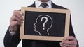 Questionmark head image on blackboard in businessman hands, searching solution