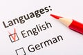 Questionnaire concept. Languages with English and German checkboxes with red pencil. Close up image