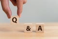 Questions and answers concept. Hand putting wood block cube with alphabet Q&A on wooden table Royalty Free Stock Photo