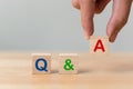 Questions and answers concept. Hand putting wood block cube with alphabet Q&A on wooden table Royalty Free Stock Photo