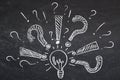 Questions, exclamation marks around lamp drawn in chalk on blackboard Royalty Free Stock Photo