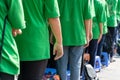Queue of Asian teenagers in green t-shirt uniform standing in line