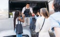 Queue of people to the food truck. Smiling salesman gives drinks to customers