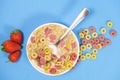 Quick breakfast cereal - rings with milk and strawberries on a blue background. Royalty Free Stock Photo