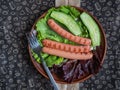 Quick breakfast with fried sausages on green salad leaves on a paper napkin with a pattern