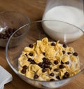 Quick cereal breakfast. Corn flakes with chocolate balls and milk in a glass bowl on a wooden table with glass jug of Royalty Free Stock Photo