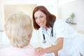 A quick checkup on a patients progress. Friendly mature nurse comforts her elderly patient with a hand to the shoulder.