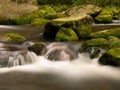 Quick mountain stream in motion over big mossy boulders.