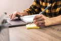 Quick note. close up hands of a businesswoman, student or freelancer in yellow shirt making a note on sticky note Royalty Free Stock Photo