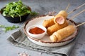 Quick snack: corn dogs on sticks. Sausages in batter on sticks on a white plate on a gray background. Royalty Free Stock Photo