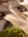 Quick stream in motion over big mossy boulders.