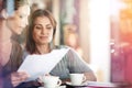 Quickly reviewing some paperwork over coffee. Two women discussing paperwork during a business meeting at a cafe. Royalty Free Stock Photo