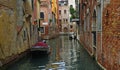 Quiet Canal in Venice with boats and crumbling walls.