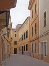 A quiet empty street in ciutadella menorca with overhanging balconies and yellow and brown painted buildings