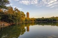 The quiet lake at sunset symmetrically reflects the trees on the bank and the water tower in the distance Royalty Free Stock Photo