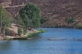 Quiet lake surrounded by hills and trees with an old partially sunken wooden bridge