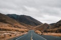 quiet and lonely long road that crosses the mountains with little vegetation and some bushes lost in the middle of