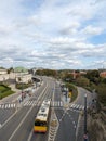 A quiet moment on the road as a bus approaches the stop, where eager passengers await, surrounded by the city\'s skyline