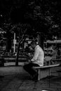 Quiet moment between shifts, a man look at his smartphone while sitting in the park. Grayscale