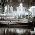 Quiet Night street of the old European city Amsterdam. Parked bicycles, lights, reflections in the river. Black and white artistic Royalty Free Stock Photo