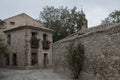 A quiet, old stone street with a rustic house, flowering plants, and a tall tree, exuding historical charm Royalty Free Stock Photo