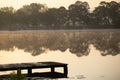 A quiet pier on a small lake or pond at sunrise with a sense of peace, solitutude, tranquility and loneliness