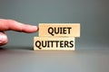 Quiet quitters symbol. Concept words Quiet quitters on wooden blocks. Beautiful grey table grey background. Businessman hand.