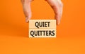 Quiet quitters symbol. Concept words Quiet quitters on wooden blocks. Beautiful orange table orange background. Businessman hand.