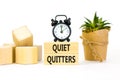 Quiet quitters symbol. Concept words Quiet quitters on wooden blocks. Beautiful white table white background. Black alarm clock.