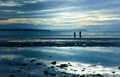 Quiet scenic beach at sunset with family walking