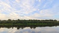 On a quiet summer evening, after sunset, the sky with feathery clouds over the river takes on pink hues and is reflected in the ca Royalty Free Stock Photo